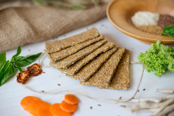 Crispbread tightened by a rope. Healthy food on a white background besid the ingredients in a wooden plate. .Lettuce with carrot near bread cakes