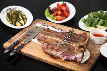 Medium-roasted steak cut into pieces on a wooden board with sauce and seasonings. Delicious steak. Beef steak medium rare on vegetable cushion. Beef steak on wooden plate. 