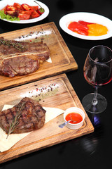 Medium-roasted steak cut into pieces on a wooden board with sauce and seasonings. Delicious steak. Beef steak medium rare on vegetable cushion. Beef steak on wooden plate. 