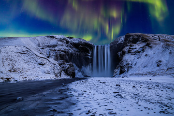 Skogafoss waterfall in the winter at night under the northern lights. Iceland. - obrazy, fototapety, plakaty