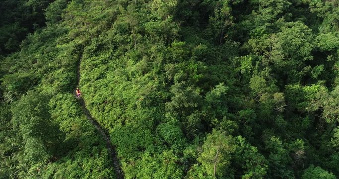 Aerial view of woman ultramarathon runner running up on mountain slope at tropical rainforest,4k