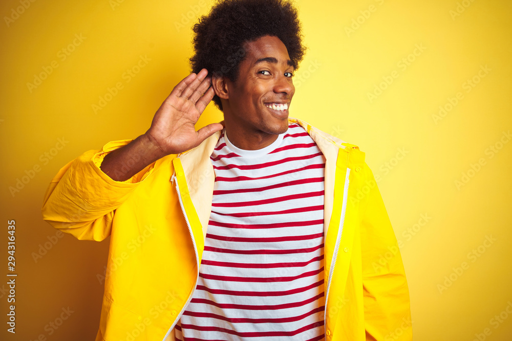 Sticker african american man with afro hair wearing rain coat standing over isolated yellow background smili