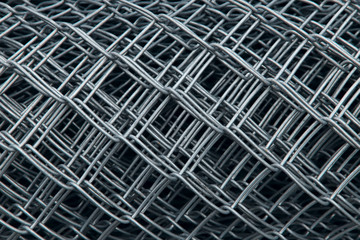 Metal mesh roll texture background. Gray metallic mesh cells in a roll. Close-up, cropped shot, horizontal. Construction and production concept.