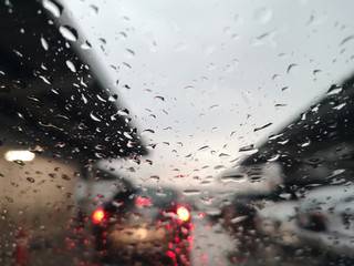 Blured background with rains drop on glass and cars on the road, Road view through car window blurry with rain and traffic jam in car park.