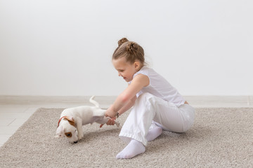 Pet, children and animal concept - Child girl holding a puppy by the paws