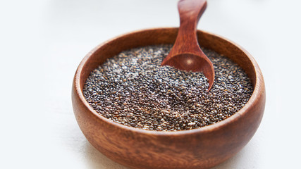 Nutritious chia seeds on a white background. chia seeds in bowl and a spoon on kitchen table top view. Healthy and diet superfood product.