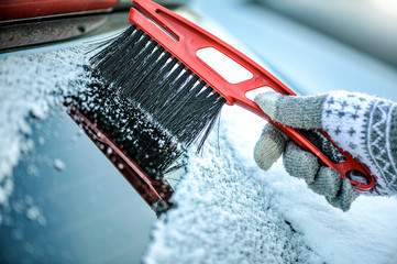 Cleaning snow from car window. Removing snow from windshield.