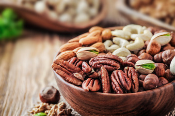 Nuts mixed in wooden bowl. Nuts on wood table with color background