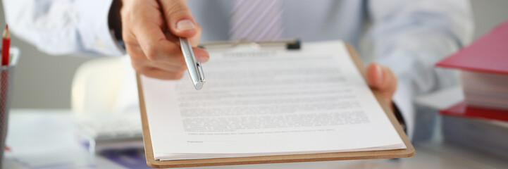 Male arm in suit offer contract form on clipboard pad and silver pen to sign closeup. Strike a bargain for profit white collar motivation union decision corporate sale insurance agent concept - obrazy, fototapety, plakaty