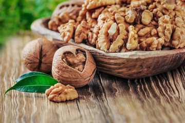 Walnuts in bowl. Walnut kernels and whole walnuts on wooden table. Walnut heart.