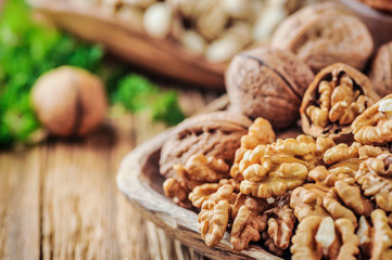 Walnuts in bowl. Walnut kernels and whole walnuts on wooden table.