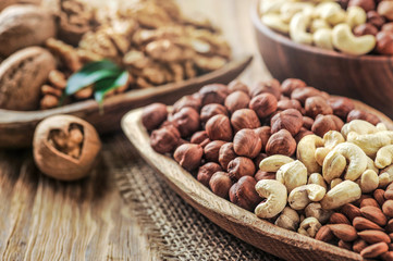 Mix nuts on wooden table. Nuts with walnut heart. Fresh raw nuts in bowls.