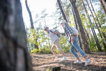 Husband holding hand of wife while hiking in forest together