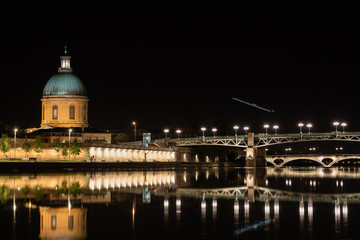 Fototapeta na wymiar Dôme de la chapelle de la Grave et le pont Saint-Pierre de Toulouse, survolé par un avion de nuit