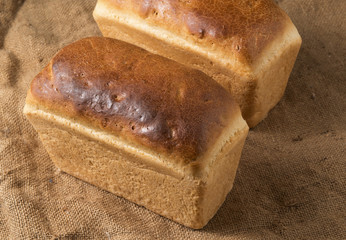 Two loaves of white bread on a rough cloth