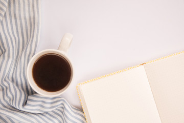 Obraz na płótnie Canvas White office desk table with blank notebook page with cup of coffee. A white Cup of coffee and book on a white background. Workplace writer or freelancer. flat lay. copy space. the view from the top.