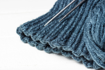 Knitted material, knitting needles and skein on white background, copy space