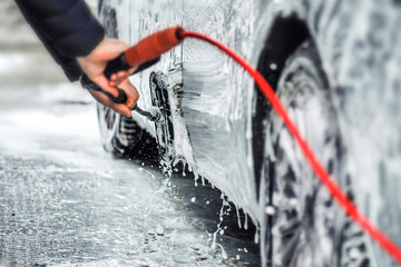 Car washing at carwash station with brush and foam. Cleaning car with soap and high pressure water....