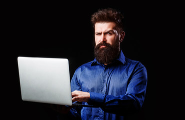 Holding laptop computer. Serious handsome bearded man worker laptop. Bearded male businessman holding a computer in his hands isolated on black background. Young businessman using his laptop, pc