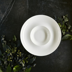 Exquisite serving white restaurant plate template on natural dark stone and leaves background