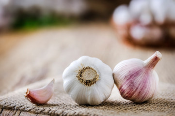 Fresh garlic on vintage table. Garlic cloves. Peeled garlic bulbs on jute.