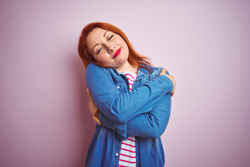 Beautiful redhead woman wearing denim shirt and striped t-shirt over isolated pink background...
