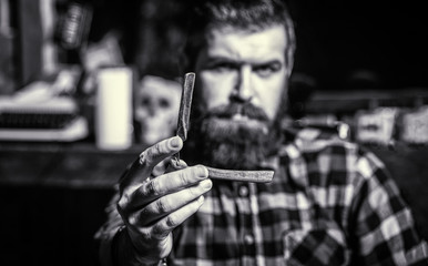 Handsome bearded hairdresser is holding a straight razor while at the barbershop. Straight razor, barbershop, beard. Mens haircut. Man in barbershop. Barber shop. Vintage straight razor.