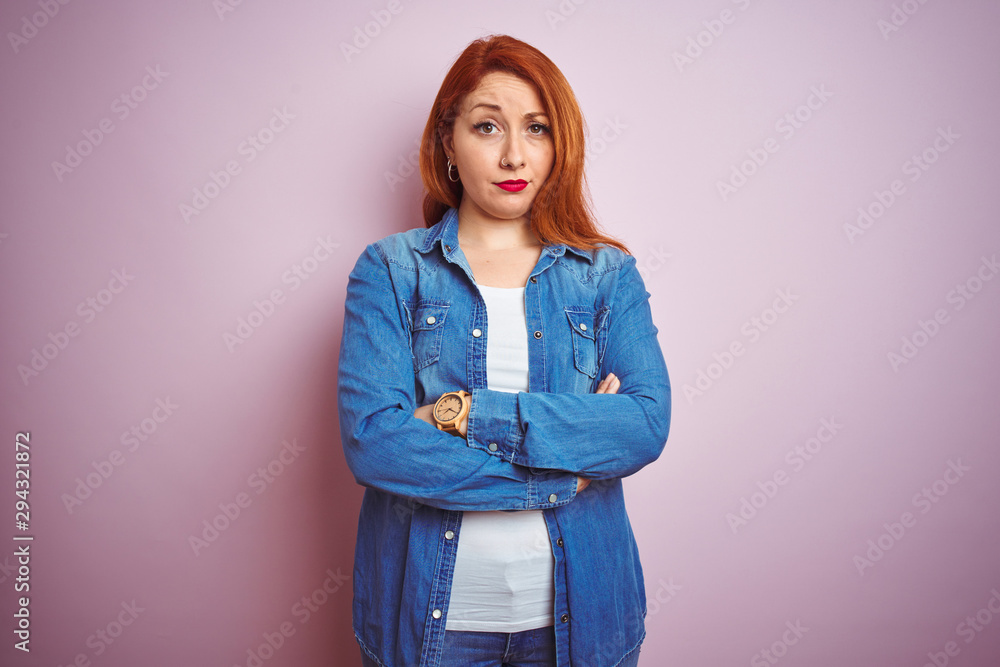 Canvas Prints Youg beautiful redhead woman wearing denim shirt standing over isolated pink background skeptic and nervous, disapproving expression on face with crossed arms. Negative person.