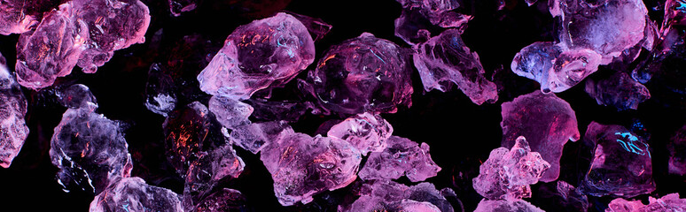 panoramic shot of transparent ice cubes with purple illumination isolated on black
