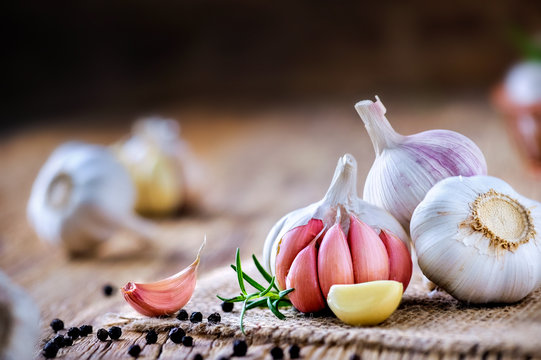 Garlic cloves on wooden table with jute. Fresh garlic bulbs and peeled violet garlic and black pepper.