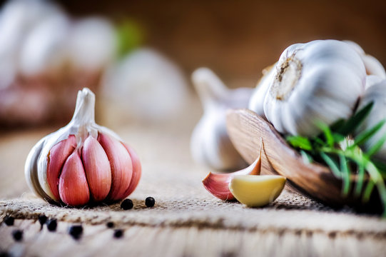 Garlic cloves on rustic table. Garlic in wooden bowl. Fresh peeled garlic and  bulbs.