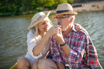 Bearded husband drinking tea having boat trip with wife