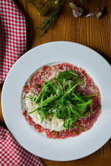 Fresh Vitello tonnato (dish of cold, sliced veal) with arugula and parmesan mushrooms on white plate. Close up view. Italian cuisine. Food photo background.