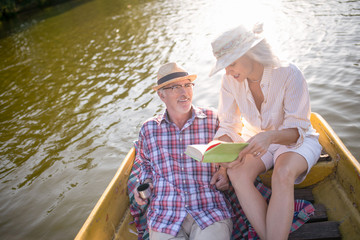 Wife reading book for husband while having boat trip
