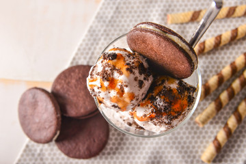 Glass with tasty ice cream and chocolate cookies on table, closeup