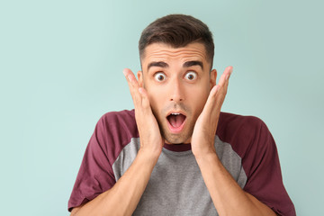 Surprised young man on color background