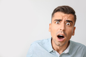 Shocked young man on light background