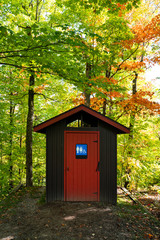 Gorgeous red and brown public toilet in the middle of the woods, Gatineau Park ,Quebec, Canada.