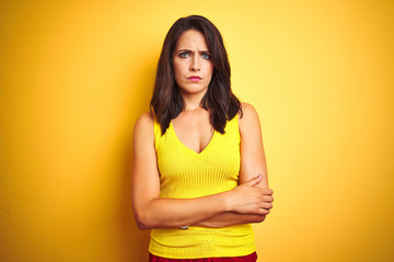 Obraz premium Young beautiful woman wearing t-shirt standing over yellow isolated background skeptic and nervous, disapproving expression on face with crossed arms. Negative person.