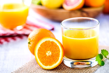 Clear glass of fresh pressed orange juice. Orange juice on table with half orange and mint leaf. Multivitamins
