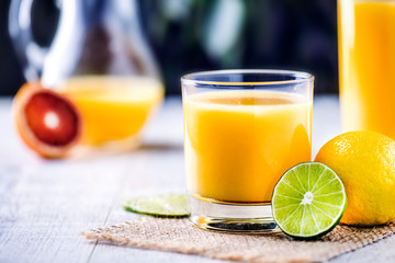Orange nectar concept. Glas of orange juice on tabe with lime and lemon.