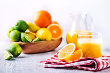 Orange juice on white table. Orange isolated with bowl full of tropical fruits on white background.