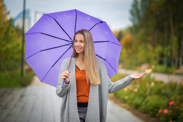 Portrait of a girl with a purple umbrella on a background of an autumn park
