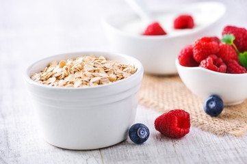 Fresh white yoghurt with raw forest fruits. Rasberries in white yoghurt in bowl on white table. Best meal for healthy breakfast.