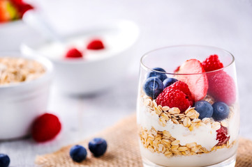 White yogurt with forest fruits. Raspberries and blueberies in clear glass with yogurt.