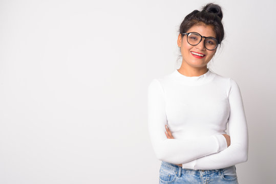 Happy young beautiful Persian woman with eyeglasses smiling with arms crossed