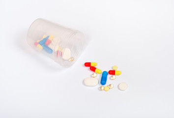 Transparent glass with different pills or drugs isolated. Medicine concept. The medicine bottle and drug tablets isolated on white background. Copy space.