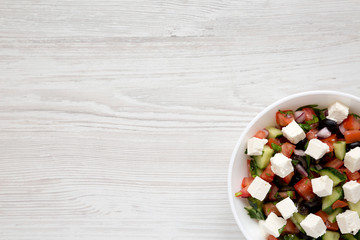 Homemade Shepards salad with cucumbers, feta and parsley in a white bowl, top view. From above, overhead. Space for text.