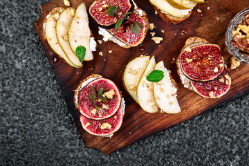 Bruschetta and Crostini with pear, ricotta cheese, honey, figs, nuts and herbs. Breakfast toasts or snack sandwiches. Antipasto. Italian food. Top view. Copy space.