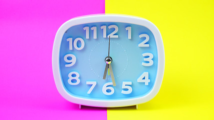 Blue Alarm clock face beginning of time 06.30 on Yellow and pink background, Copy space for your text, Time concept..
